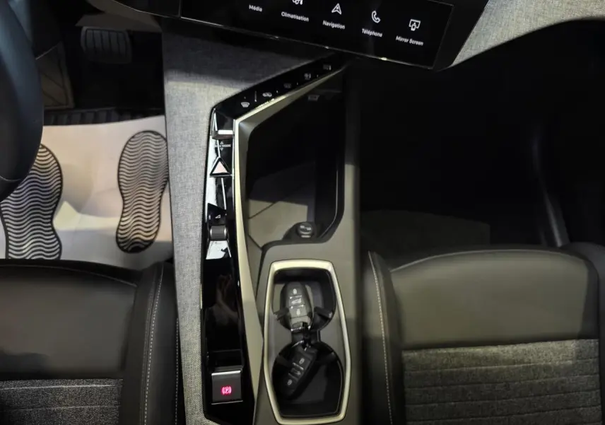 Vue plongeante sur la console centrale du Peugeot 3008 2025, avec clés, sellerie tissu et cuir noir.