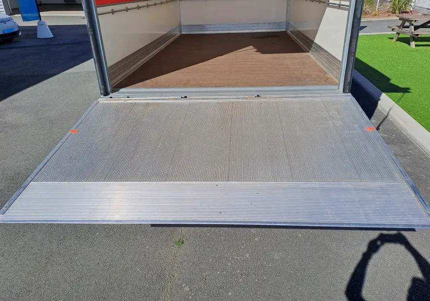 Vue arrière du Nissan Interstar châssis cabine blanc 2024 avec porte arrière ouverte et plancher en bois visible.