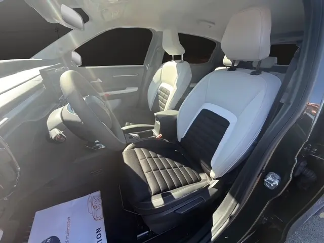 Vue intérieure côté conducteur de la Citroën C3 Aircross hybride 2026, sièges bicolores noir et blanc avec volant cuir.