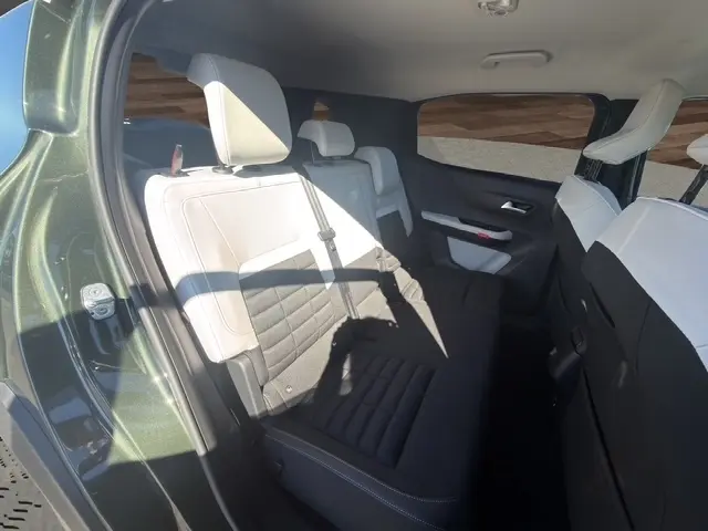 Vue intérieure côté gauche des sièges arrière noirs et blancs du Citroën C3 Aircross hybride vert 2026, avec appuie-têtes visibles.