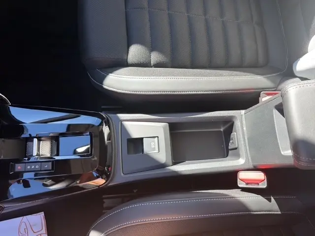 Vue plongeante sur la console centrale noire et les sièges en tissu gris foncé du Citroën C3 Aircross hybride 2026.