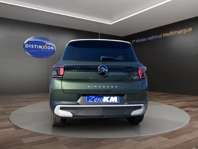 Vue arrière d'un Citroën C3 Aircross vert foncé avec logo central et feux LED distinctifs en intérieur showroom.