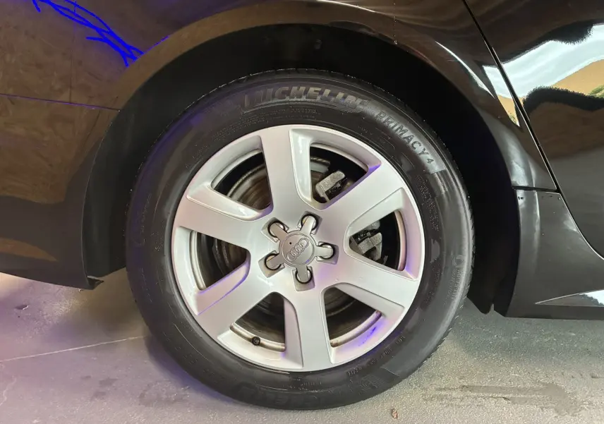 Gros plan sur la roue arrière droite noire d'une Audi A6 Avant 2017 avec jante argentée cinq branches.