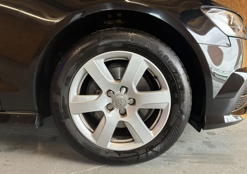Gros plan sur la roue avant droite d'une Audi A6 Avant noire de 2017, avec jante argentée et pneu Goodyear.