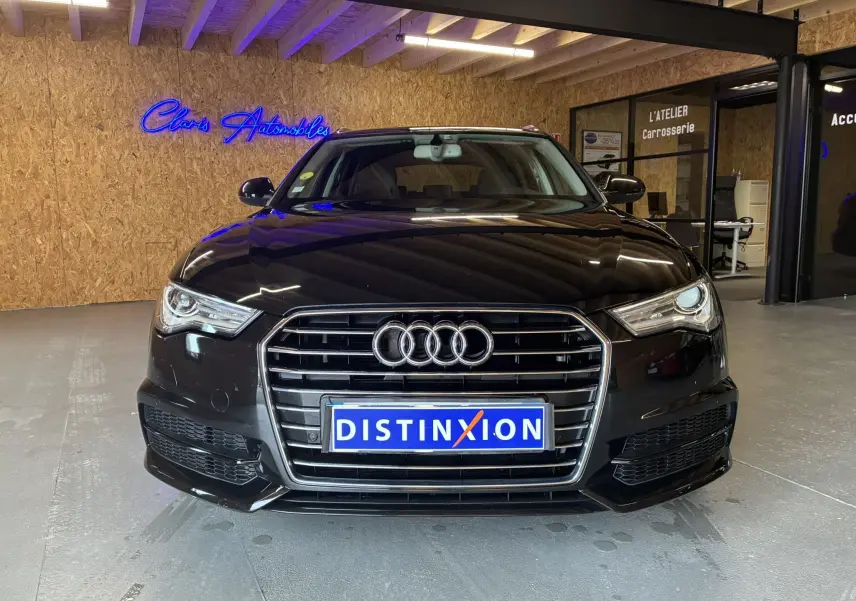 Vue frontale d'une Audi A6 Avant noire 2017 avec calandre chromée et logo quatre anneaux bien visible en intérieur showroom.