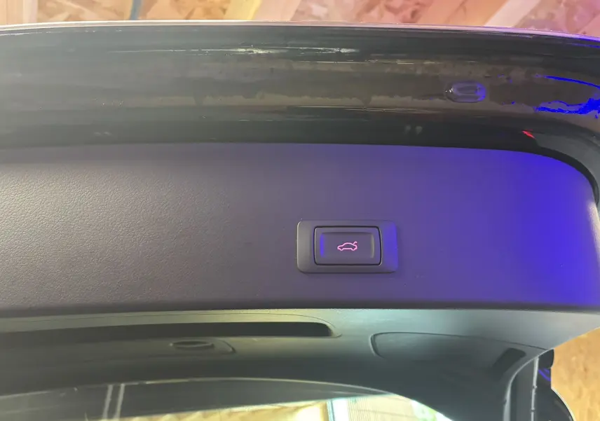 Bouton d'ouverture électrique du hayon sur la partie intérieure du coffre d'une Audi A6 Avant noire 2017.