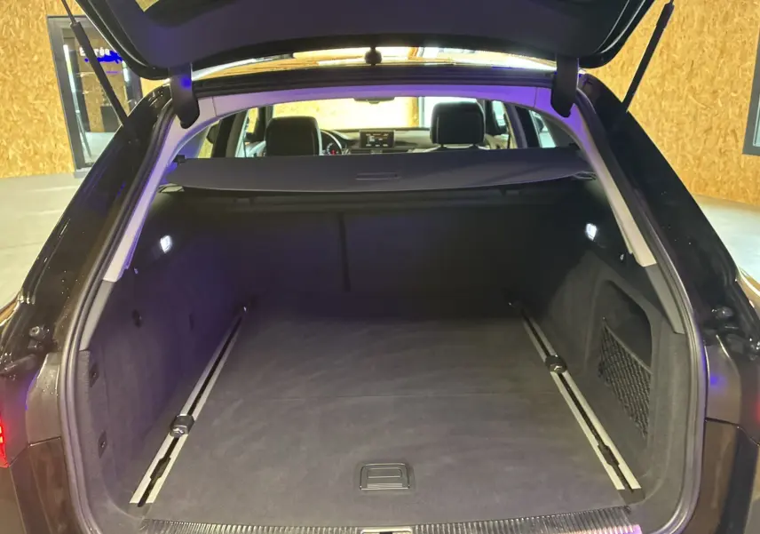 Coffre ouvert d'une Audi A6 Avant noire 2017, vue arrière montrant un espace de chargement spacieux et bien éclairé.