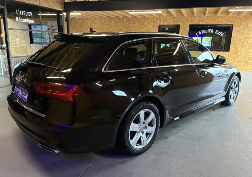 Audi A6 Avant noire vue de 3/4 arrière droit, mettant en valeur ses feux arrière LED et ses jantes argentées.