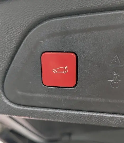 Bouton rouge d'ouverture électrique du hayon sur le panneau intérieur du coffre d'un Citroën C5 Aircross blanc.