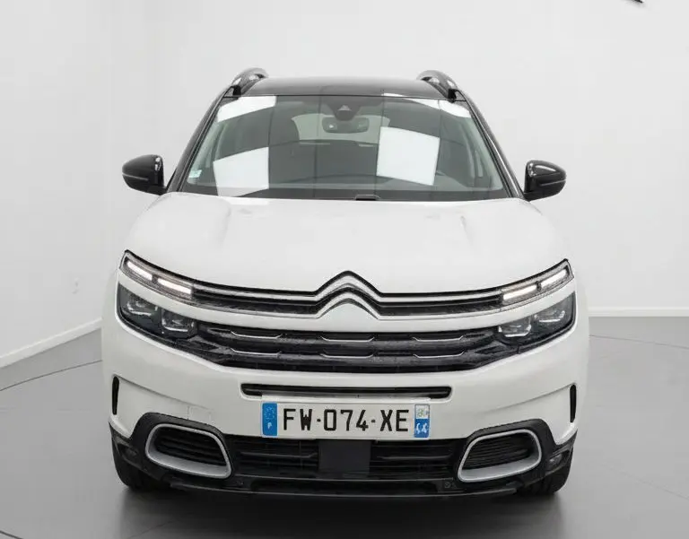 Vue frontale d'un Citroën C5 Aircross blanc nacré avec toit noir et calandre distinctive en studio.