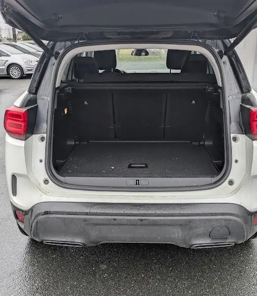 Vue arrière du coffre ouvert d'un Citroën C5 Aircross blanc nacré, montrant l'espace de chargement vide.