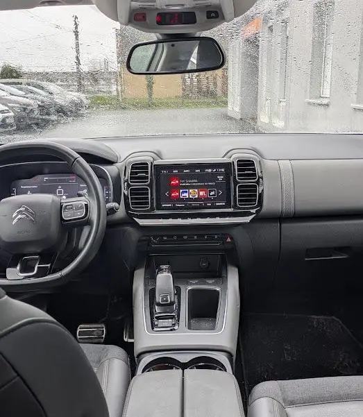 Vue intérieure avant du Citroën C5 Aircross blanc, tableau de bord moderne avec écran tactile central et volant multifonction.