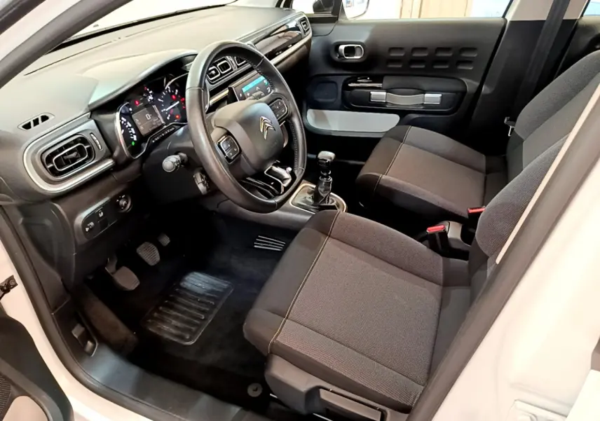 Intérieur avant droit de la Citroën C3 blanche 2019, volant cuir, tableau de bord moderne et sièges tissu gris.