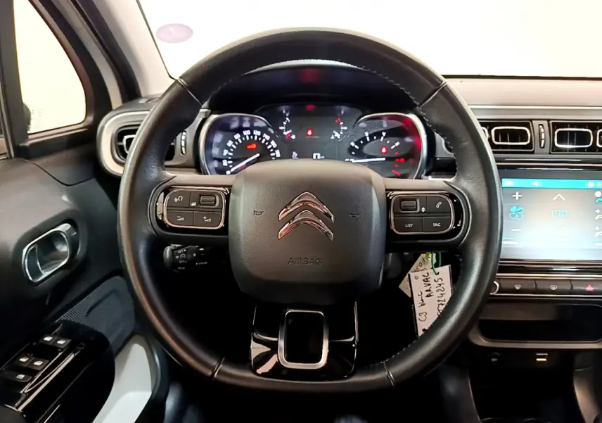 Vue intérieure centrée sur le volant cuir noir de la Citroën C3 blanche avec tableau de bord et écran tactile.