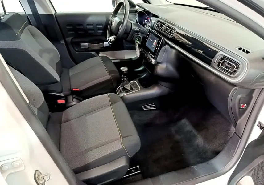 Intérieur avant droit de la Citroën C3 blanche 2019, montrant sièges gris, volant cuir et écran tactile central.