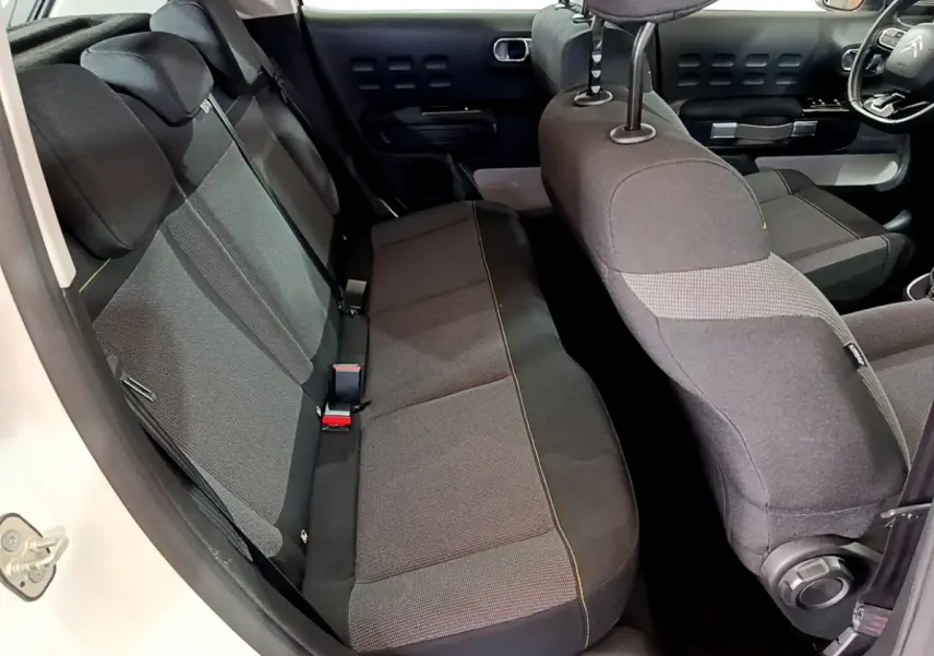 Vue intérieure côté gauche montrant la banquette arrière et partie avant des sièges de la Citroën C3 blanche.