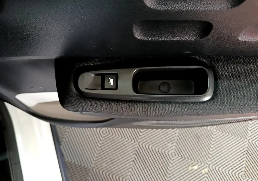Gros plan sur la commande de lève-vitre côté intérieur d'une porte noire d'une Citroën C3 blanche de 2019.
