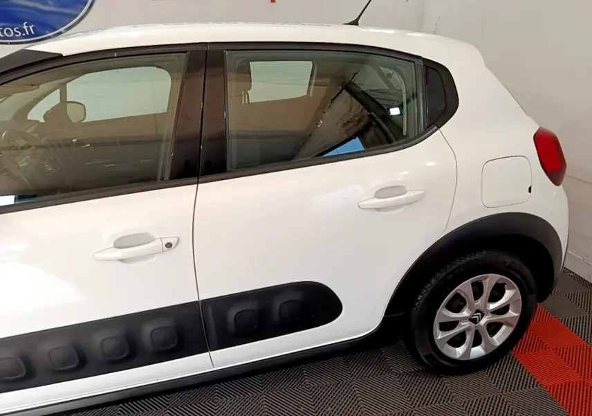 Profil côté droit d'une Citroën C3 blanche avec protections latérales noires et jantes alliage visibles.