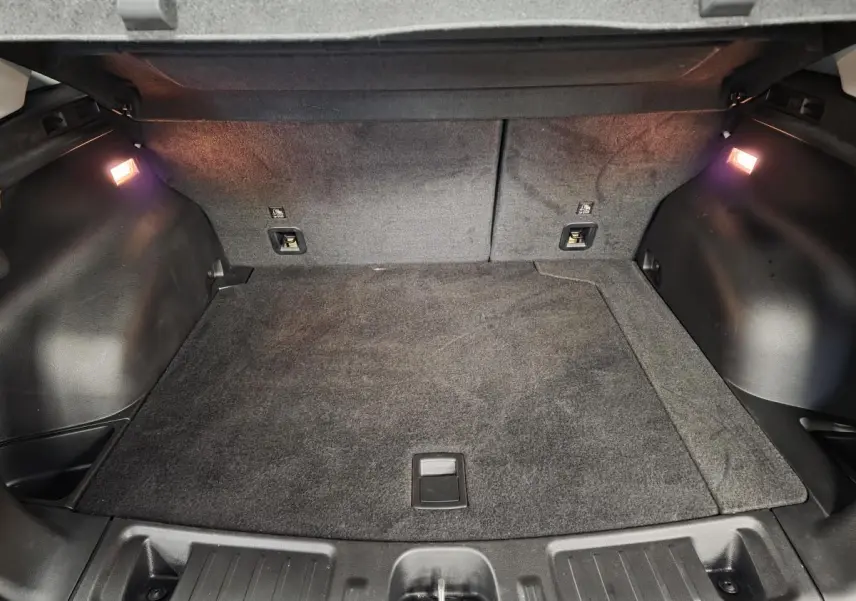 Coffre spacieux et éclairé du Jeep Compass blanc 2024, vue intérieure arrière avec tapis gris.