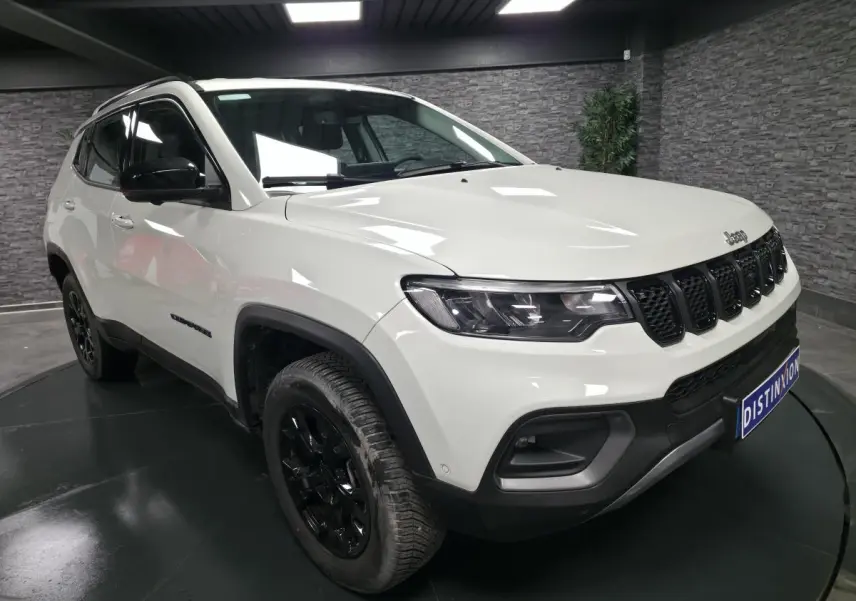Jeep Compass blanc en 3/4 avant droit, avec jantes noires et calandre à sept fentes caractéristiques.