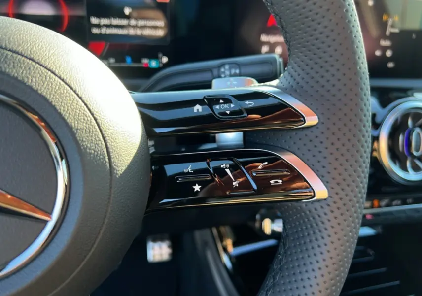 Gros plan sur le volant cuir perforé de la Mercedes Classe A 200D BVA Exclusive Design noir cosmos, avec commandes multifonctions.