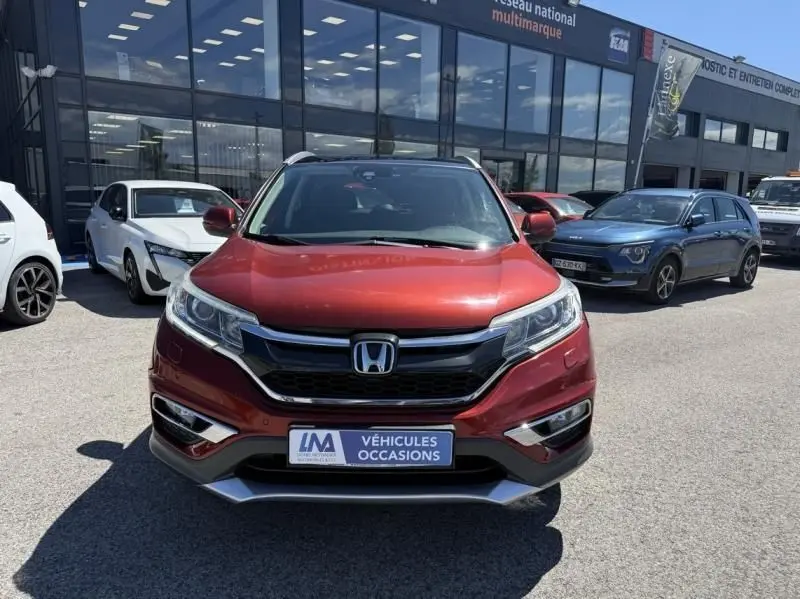 Vue frontale d'un Honda CR-V rouge métal 2017, avec calandre noire et badge Honda bien visible, en concession.