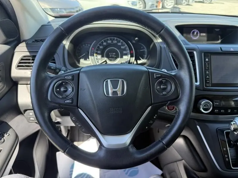 Vue intérieure centrée sur le volant noir du Honda CR-V 2017, avec tableau de bord et console centrale visibles.