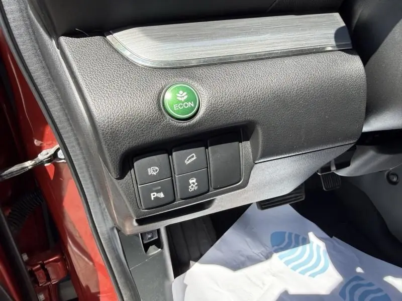 Vue rapprochée des commandes côté gauche du tableau de bord d’un Honda CR-V rouge métal 2017, avec bouton ECON vert.