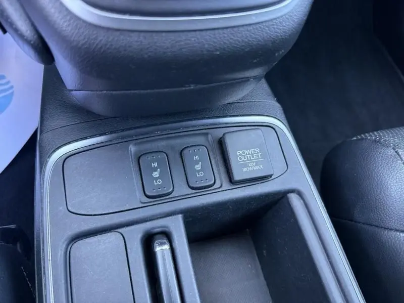 Gros plan sur la console centrale du Honda CR-V rouge métal 2017, montrant les boutons de sièges chauffants et prise 12V.