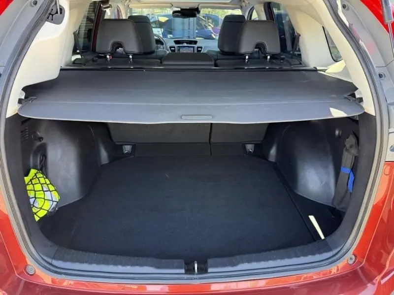 Vue arrière du coffre ouvert d'un Honda CR-V rouge métal 2017, avec cache-bagages et intérieur noir visible.