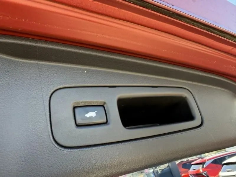 Bouton d'ouverture du coffre sur la partie intérieure de la porte arrière d'un Honda CR-V rouge métal 2017.
