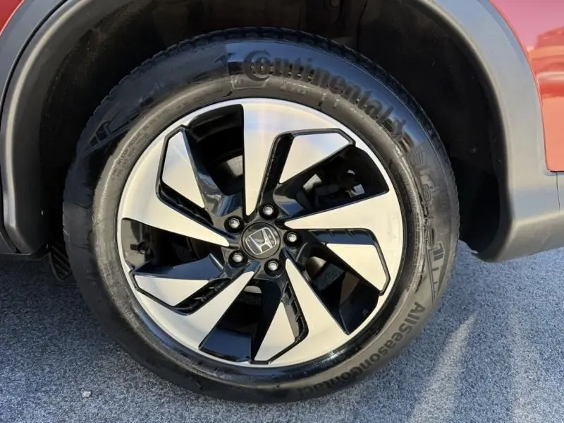 Gros plan sur la roue avant droite d’un Honda CR-V rouge métal 2017, jante alliage bicolore avec pneu Continental.