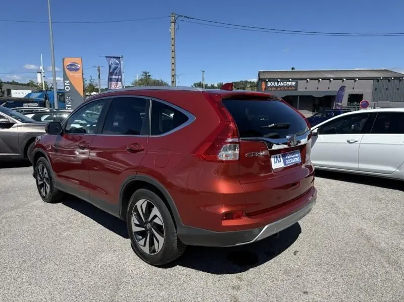 Vue 3/4 arrière droite d'un Honda CR-V rouge métal 2017 avec jantes alliage et vitres teintées, stationné en extérieur.
