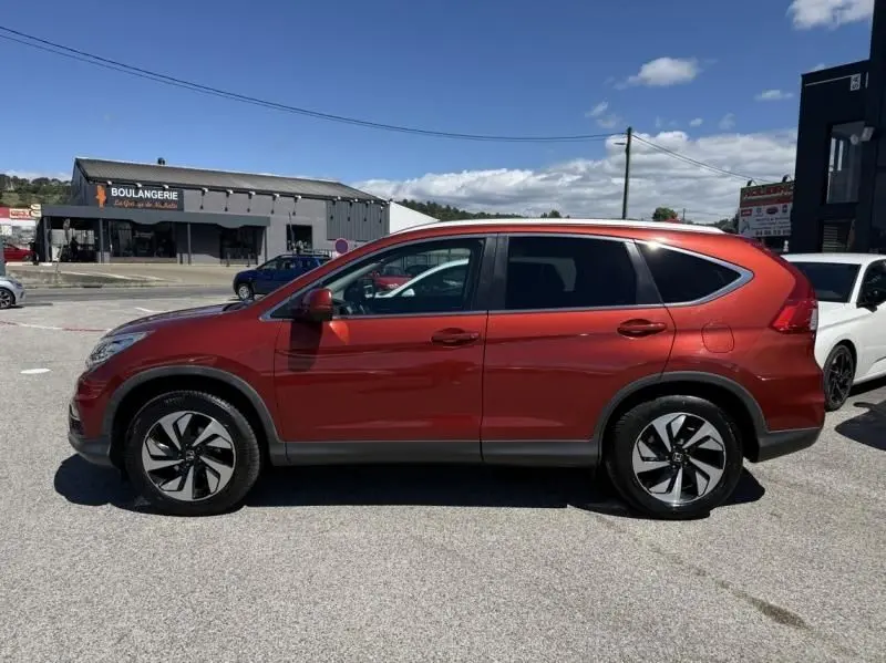 Vue de profil côté gauche d'un Honda CR-V rouge métal 2017, avec jantes alliage distinctives et vitres teintées.