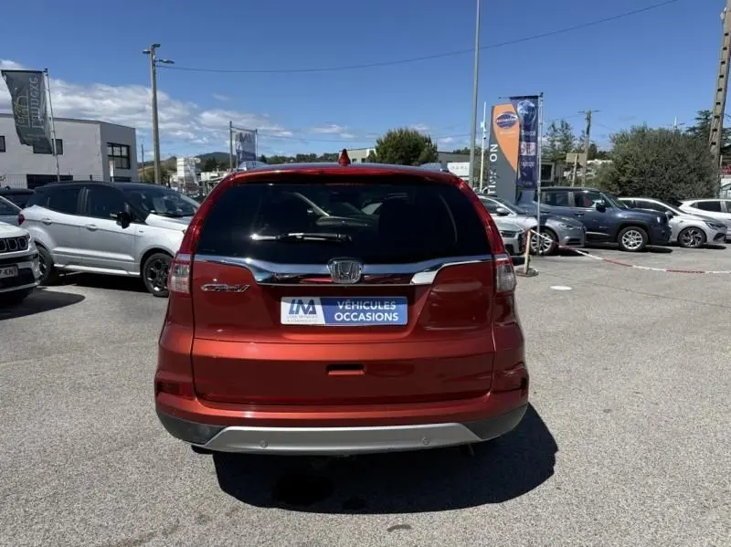 Vue arrière d'un Honda CR-V rouge métal 2017, avec logo et plaque "Véhicules Occasions" visible en concession.
