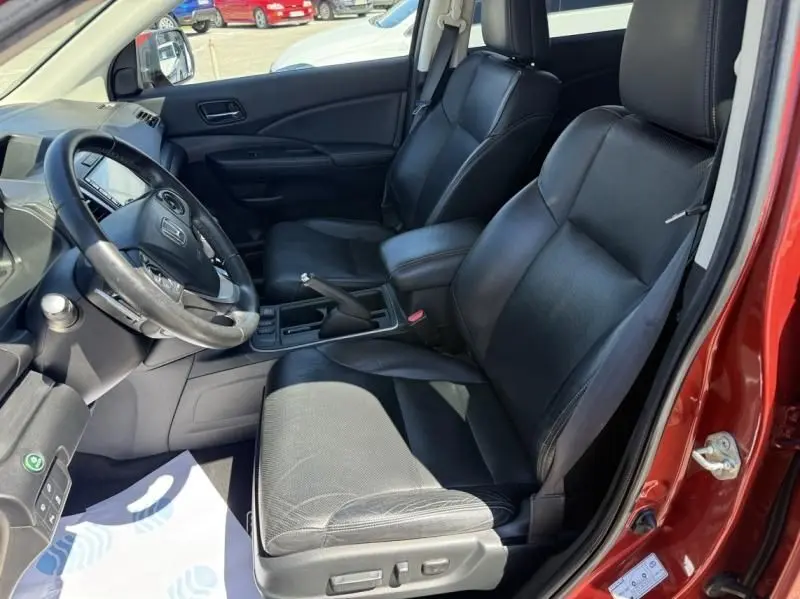Vue intérieure côté conducteur du Honda CR-V rouge métal 2017, sièges en cuir noir et tableau de bord moderne.
