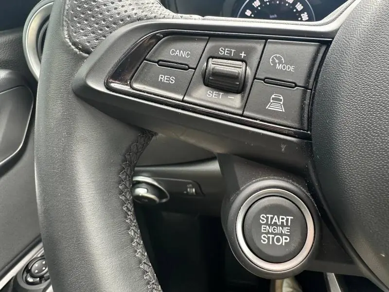 Gros plan sur le volant cuir noir de l'Alfa Romeo Tonale 2025 avec commandes de régulateur et bouton start/stop.