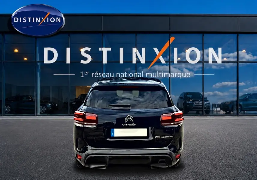 Vue arrière d'un Citroën C5 Aircross noir 2024 garé devant une vitrine avec logo Distinxion.