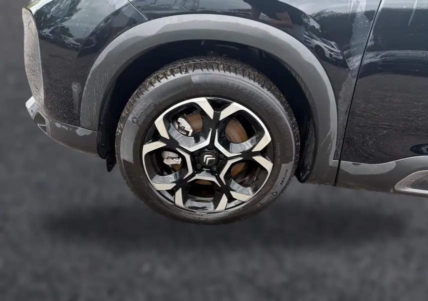 Gros plan sur la roue avant gauche noire du Citroën C5 Aircross 2024 avec jante alu bicolore distinctive.