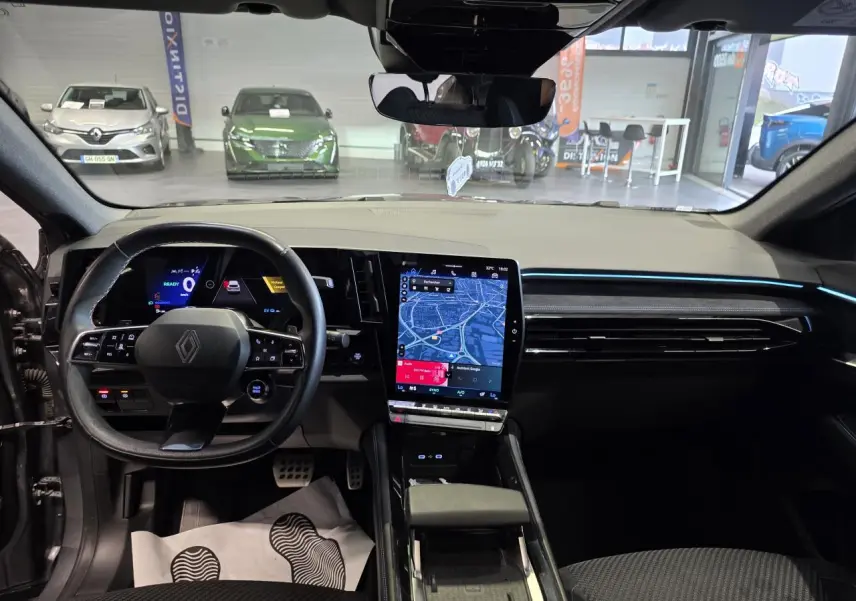 Vue intérieure avant du Renault Austral gris foncé, mettant en valeur le volant multifonction et l'écran tactile central vertical.