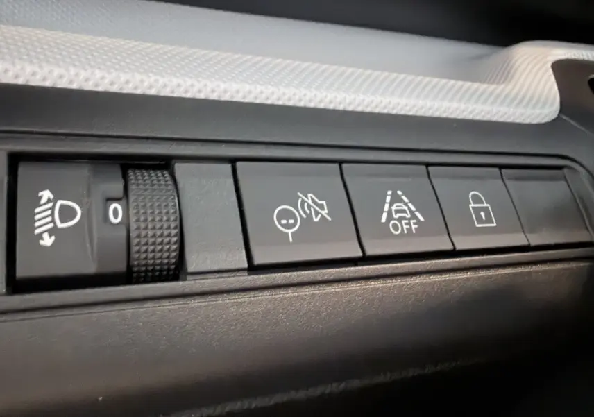 Gros plan sur les boutons de commande noirs du tableau de bord d'une Citroën C3 Aircross électrique gris foncé.