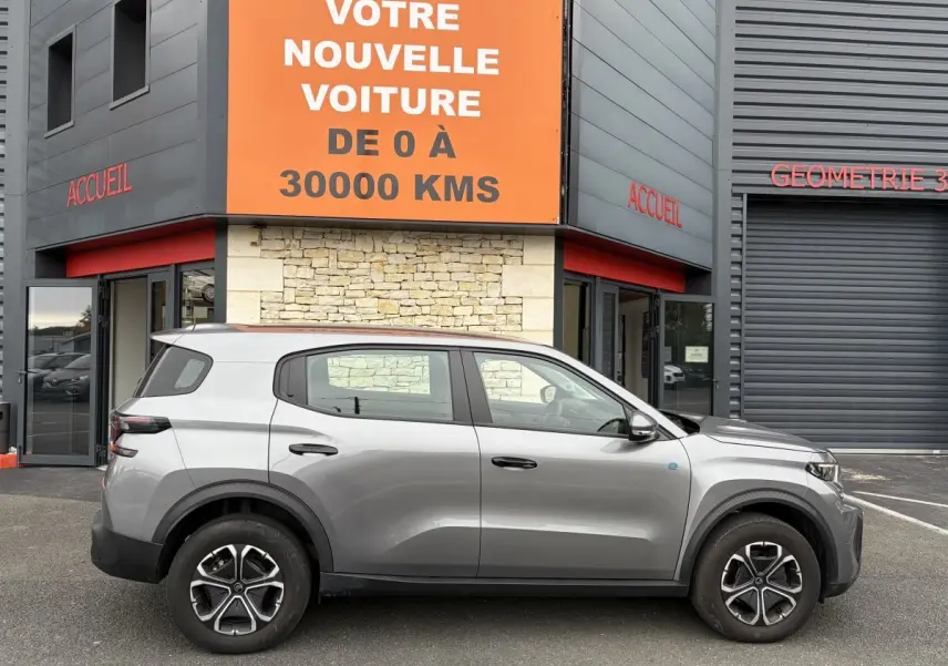 Profil côté droit d'un Citroën C3 Aircross électrique gris foncé 2025, avec jantes distinctives et détails noirs contrastants.