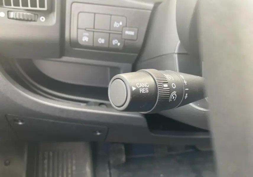 Gros plan sur la commande de régulateur de vitesse à gauche du volant dans l'habitacle du fourgon blanc Opel Movano.