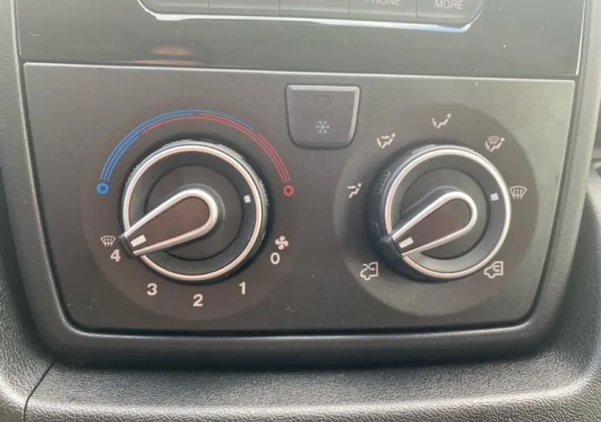 Gros plan sur les commandes de climatisation du fourgon Opel Movano blanc, avec réglages de température et de ventilation visibles.