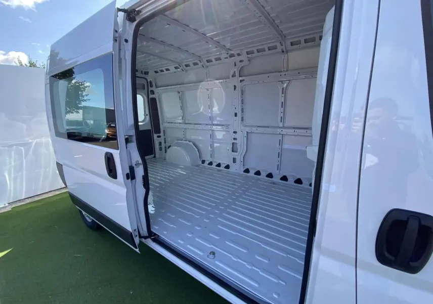 Vue latérale droite d'un Opel Movano Fourgon blanc avec porte coulissante vitrée ouverte dévoilant l'intérieur vide du compartiment de chargement.