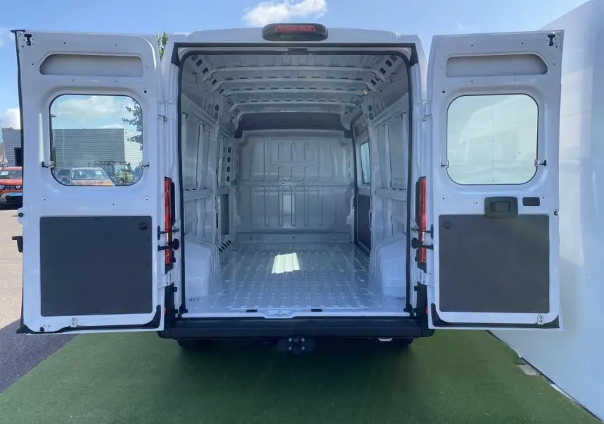 Vue arrière ouverte d'un Opel Movano Fourgon blanc 2023, montrant l'espace de chargement vide et le crochet d'attelage.