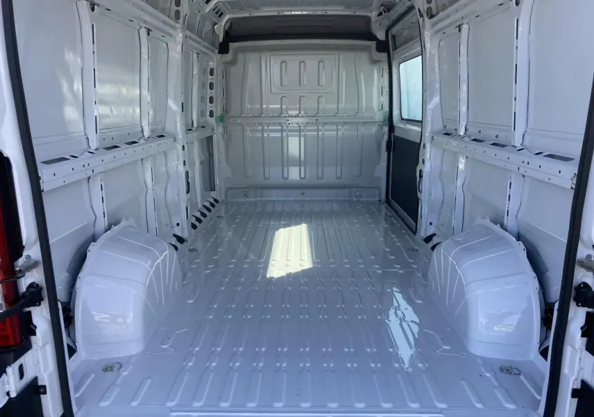 Intérieur vide du fourgon blanc Opel Movano L3H2 vu de l'arrière avec portes ouvertes et parois métalliques lisses.
