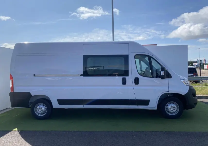 Profil droit d'un fourgon blanc Opel Movano L3H2 2023 avec porte latérale vitrée coulissante et roues acier.