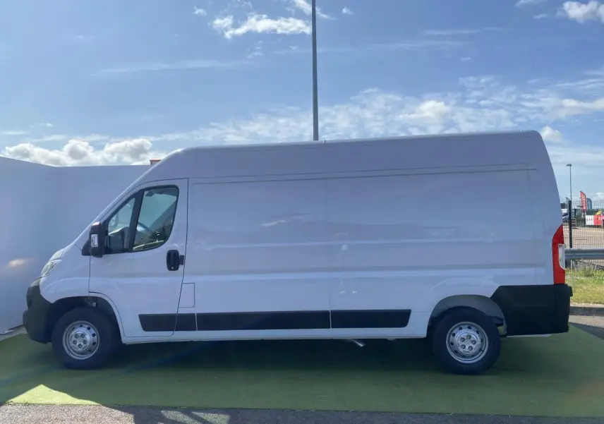 Vue latérale droite d'un fourgon blanc Opel Movano L3H2 2023 avec porte coulissante vitrée et crochet d'attelage.
