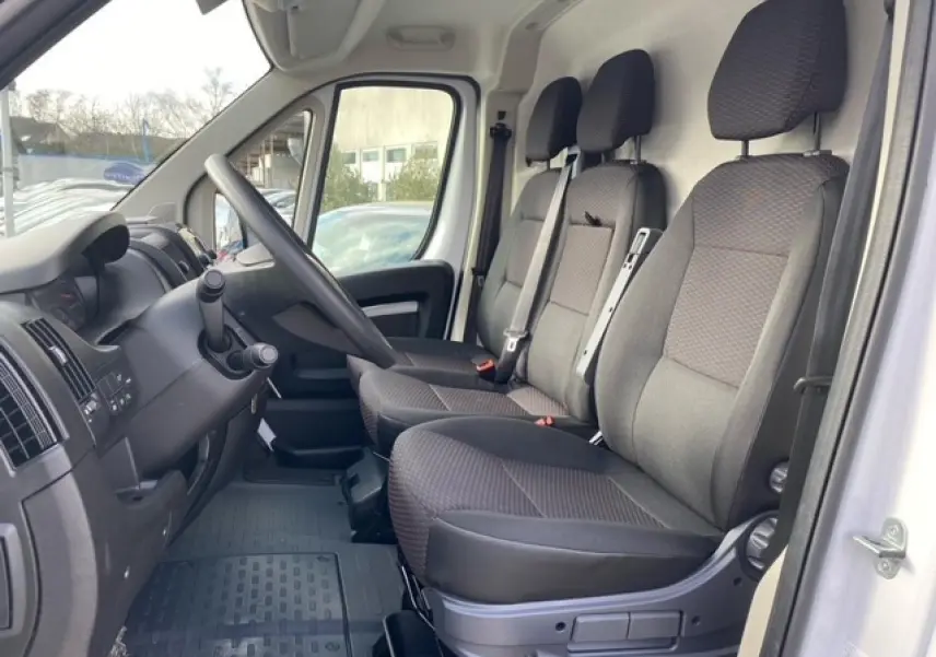 Vue intérieure côté conducteur de l'Opel Movano Fourgon blanc 2023 montrant les sièges avant et le tableau de bord.